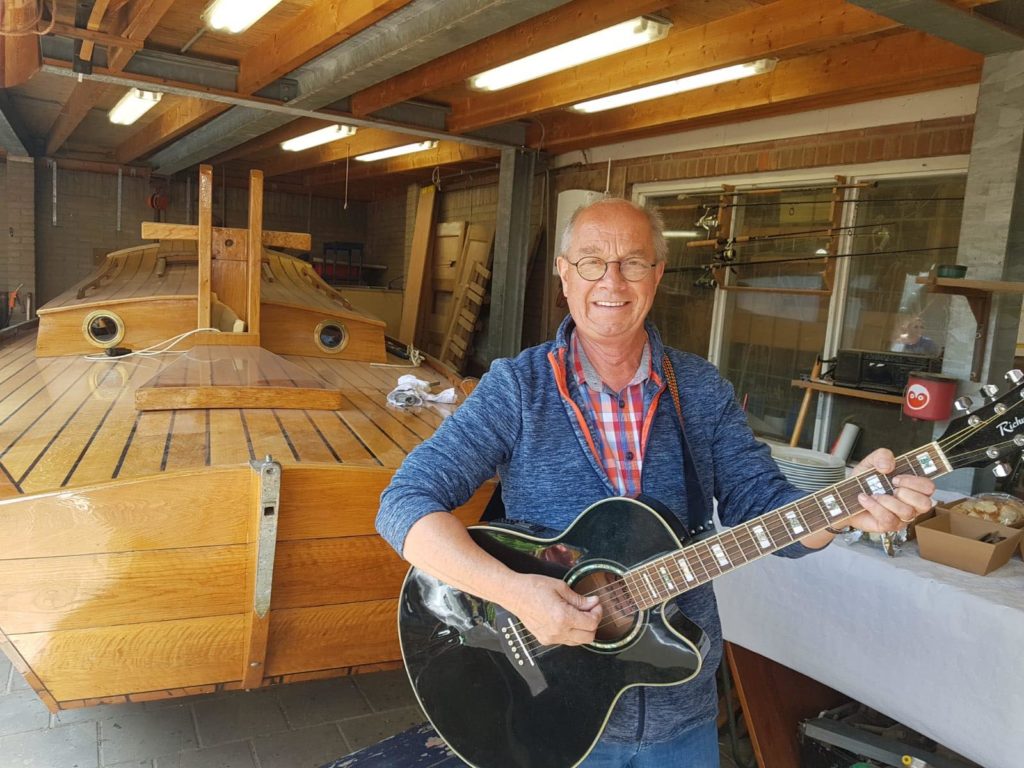 Jaap Wagenaar speelt muziek op zijn gitaar voor een boot